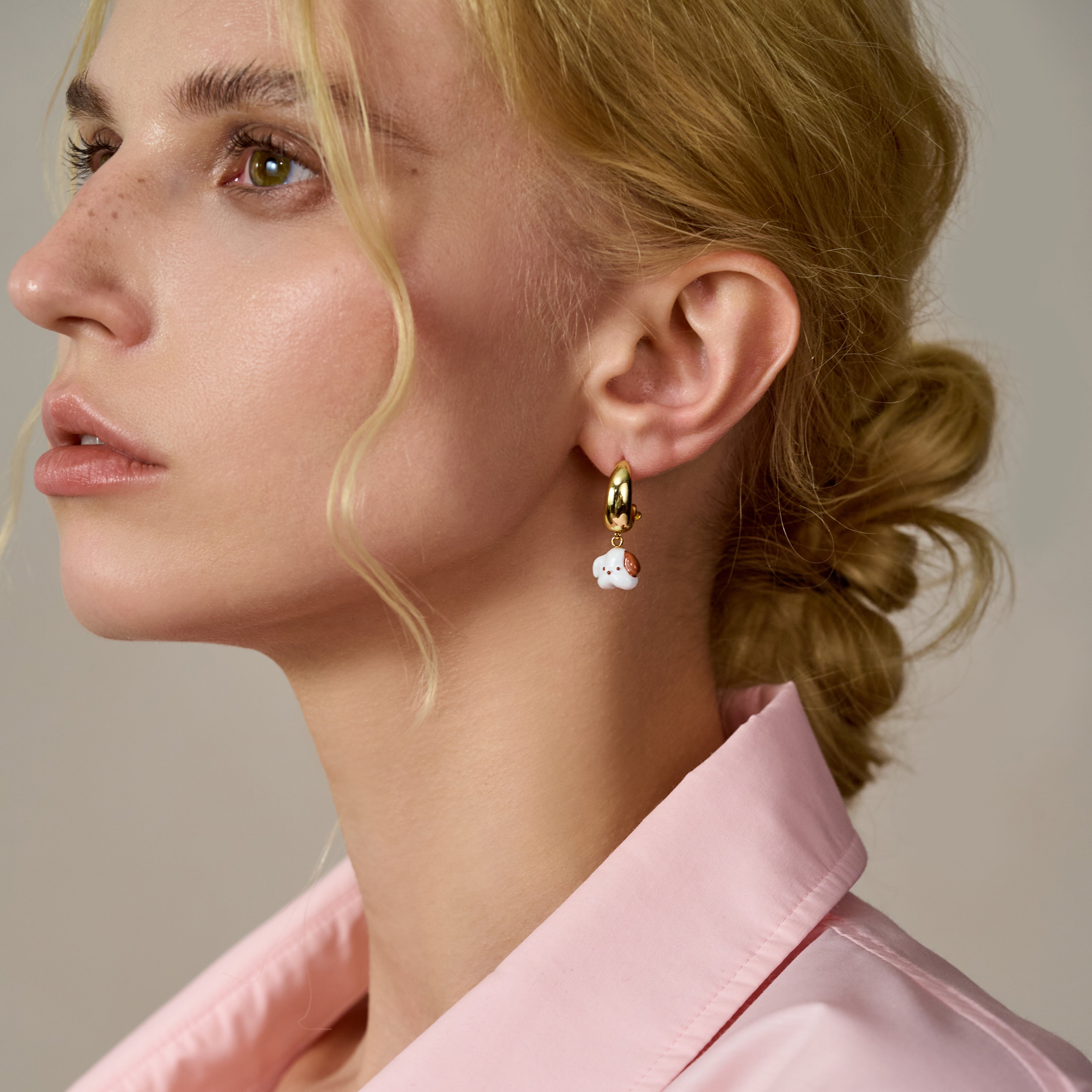 Woman wearing gold-plated hoop earring with cute white charm, elegant and stylish jewelry