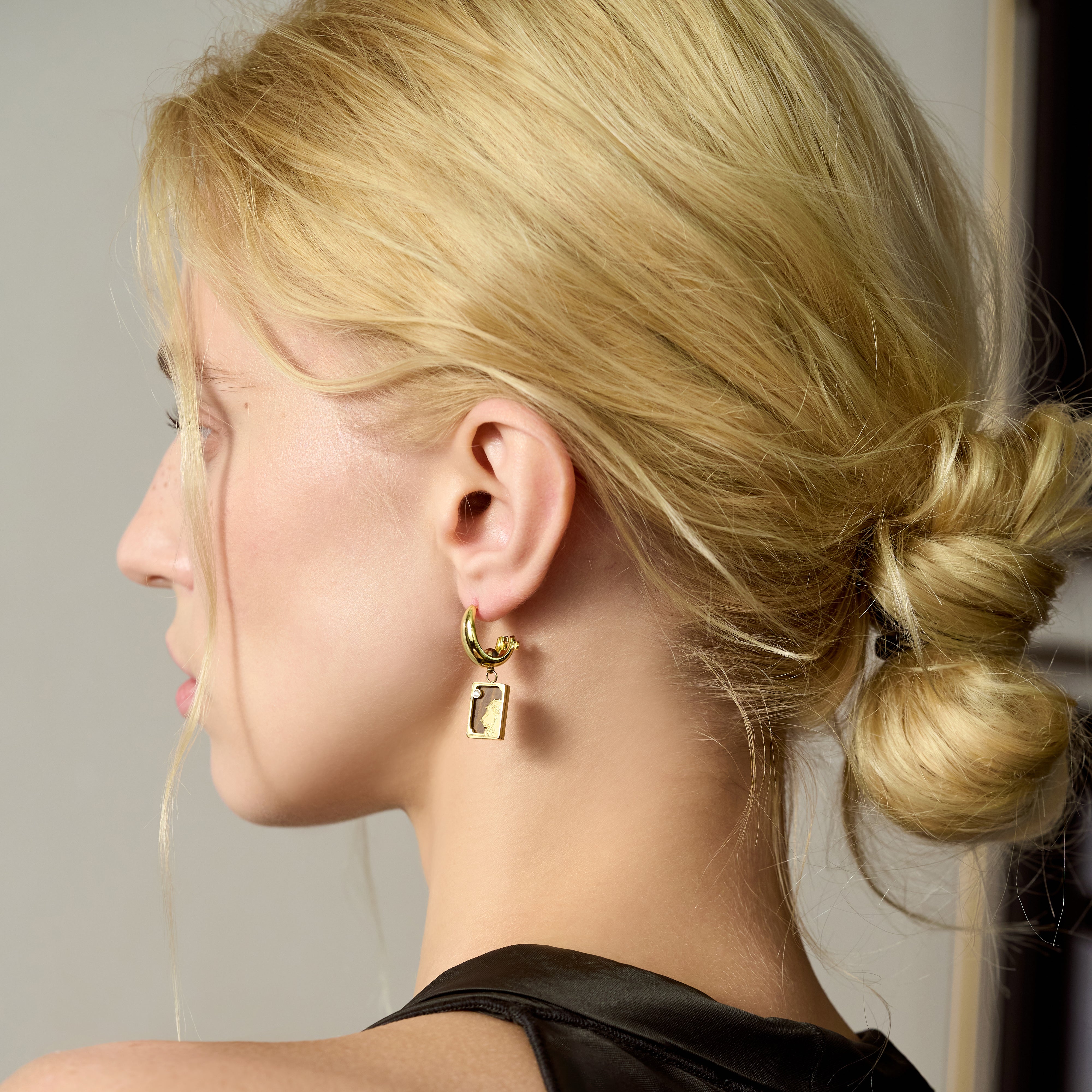 Woman with blonde hair in a low bun wearing a gold-plated statement earring