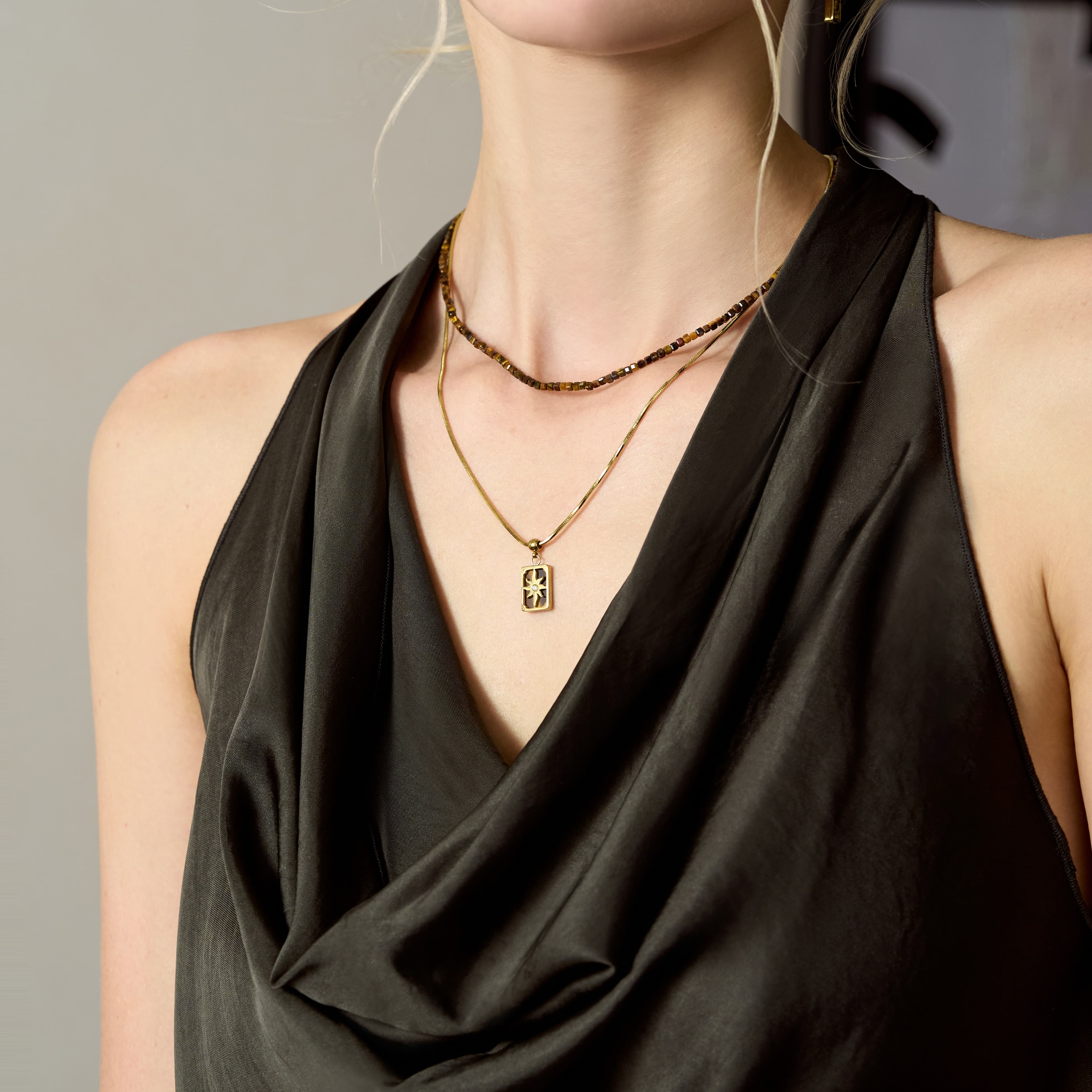 Woman wearing layered gold-plated necklaces over an elegant black satin top