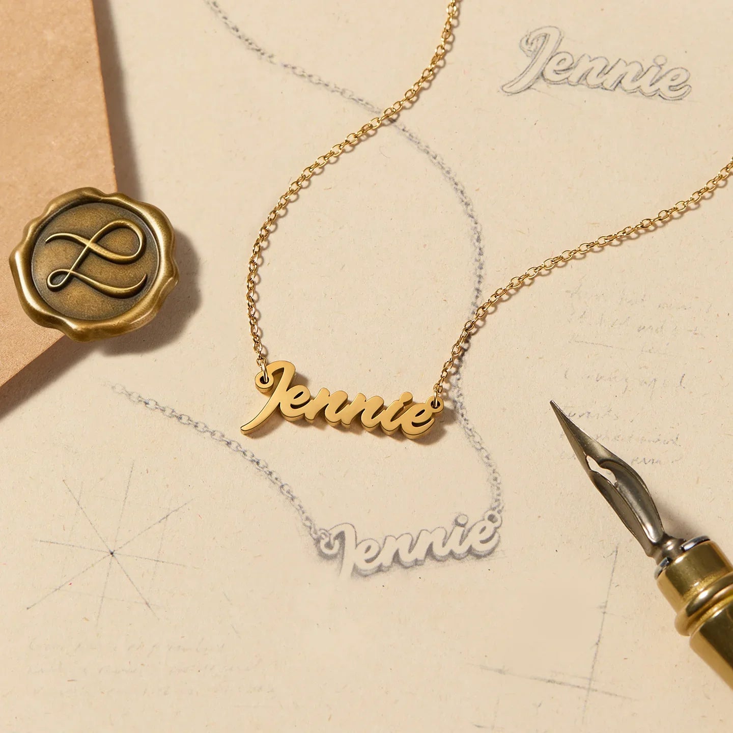 Gold-plated name necklace with 'Jennie' script on vintage stationery background.