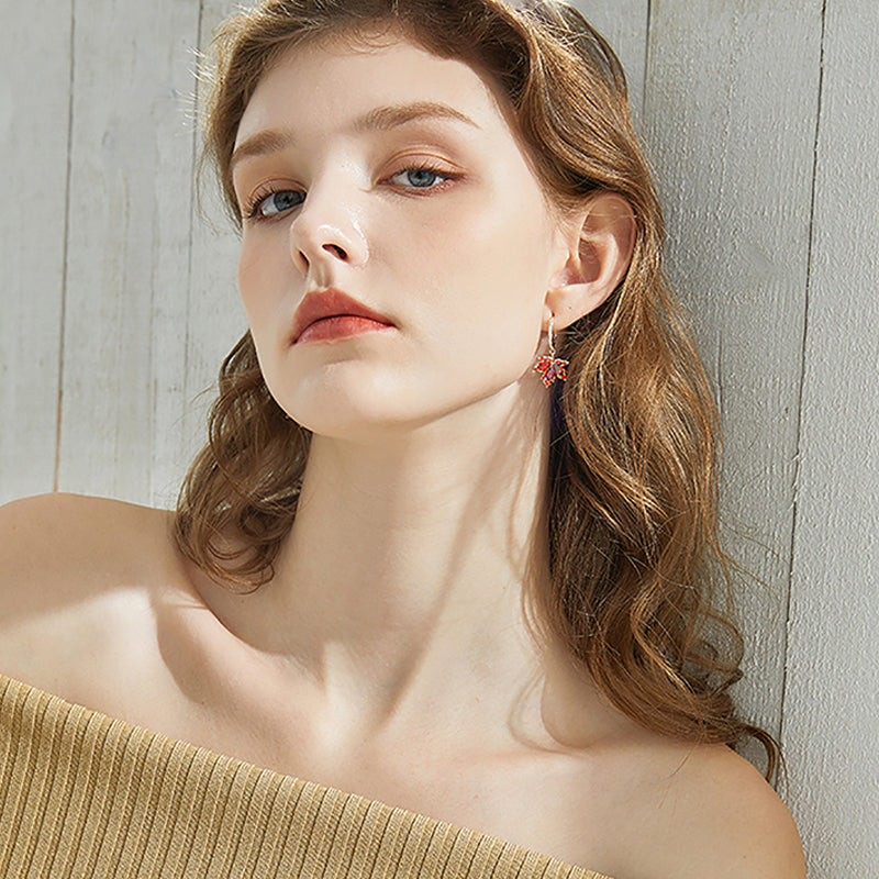 Woman wearing gold-plated statement earrings with pink gemstones, off-shoulder top