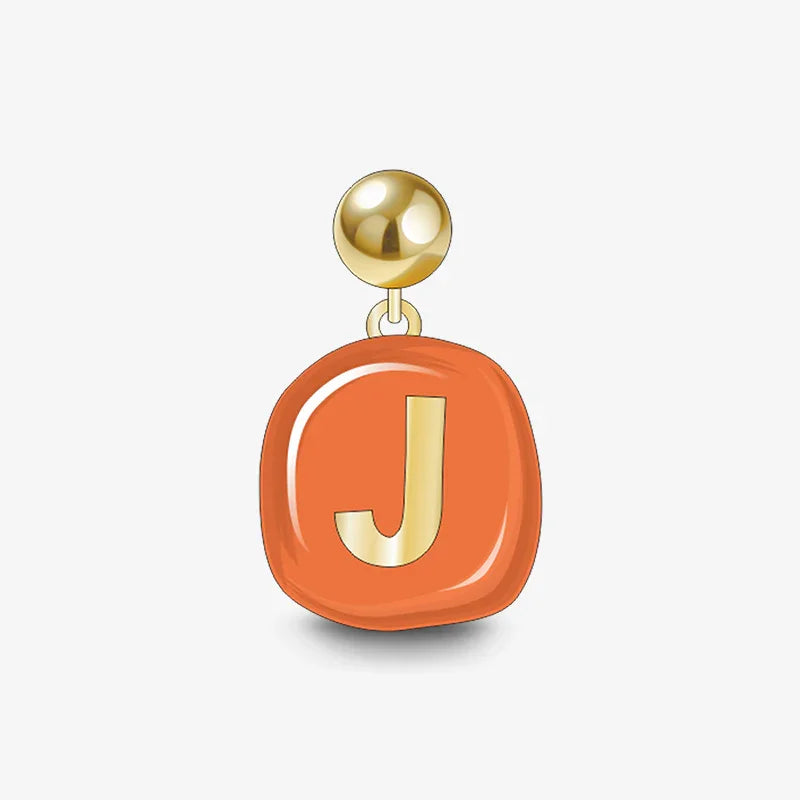 Gold-plated stud earring with orange enamel and gold letter J charm on white background