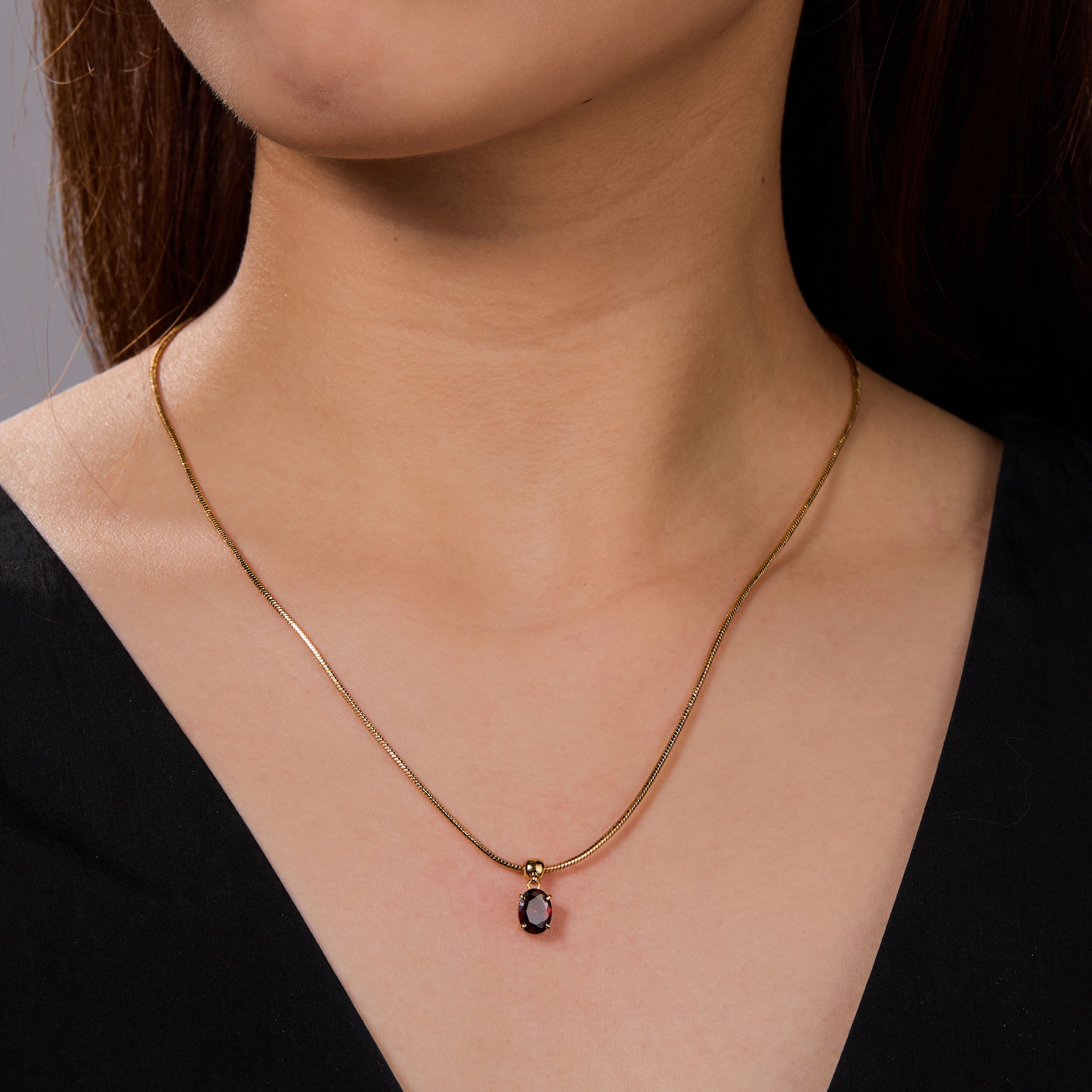 Gold-plated necklace with black gemstone pendant on woman’s neck, elegant jewelry