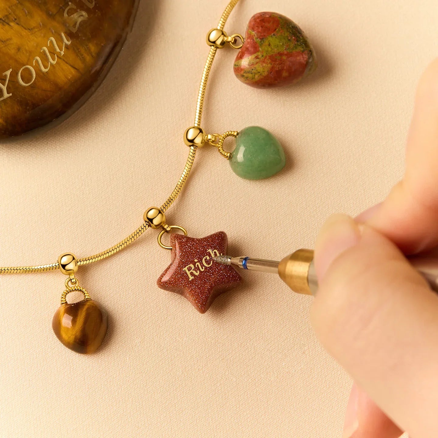 Engraving gold-plated necklace with gemstone heart and star pendants on beige fabric