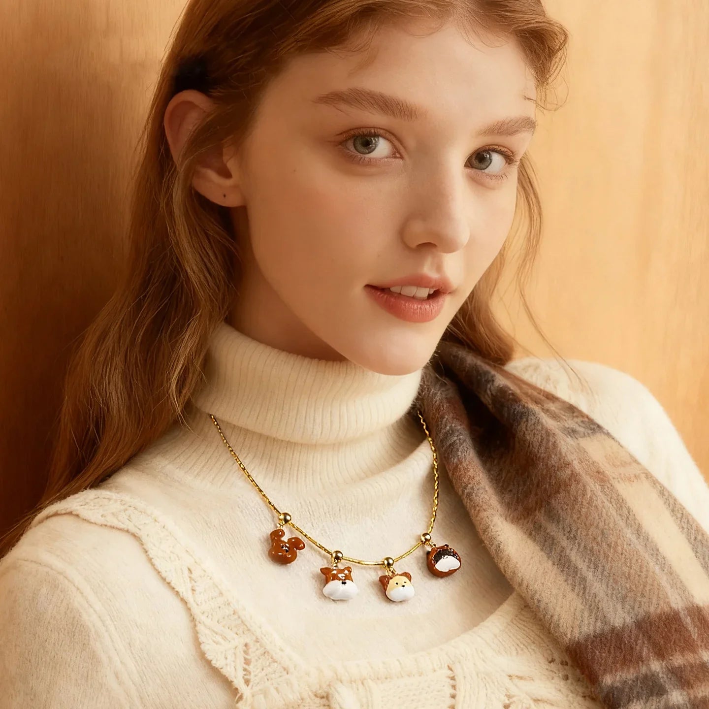 Woman wearing a gold-plated animal charm necklace with a cream turtleneck and plaid scarf