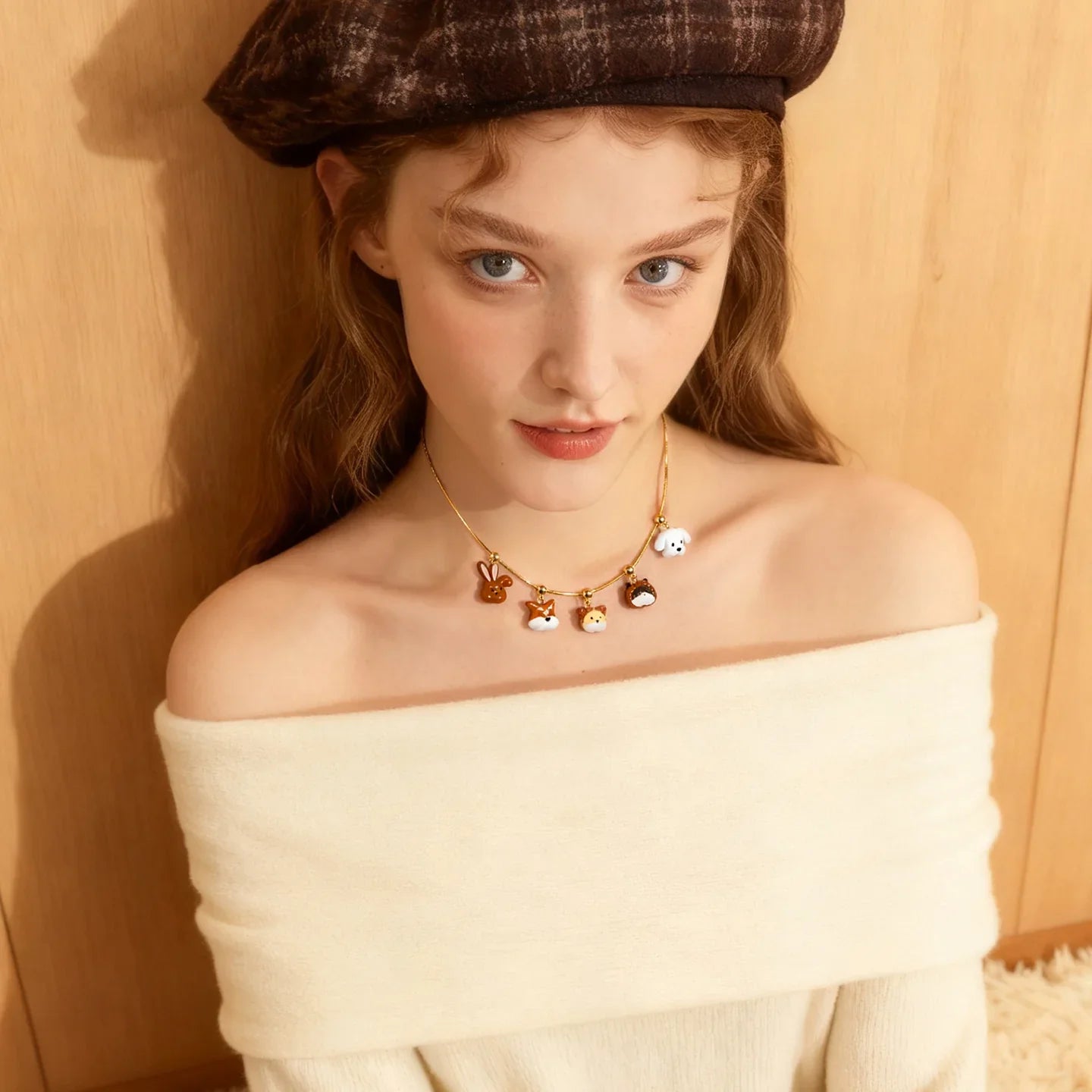 Woman wearing gold-plated animal charm necklace and off-shoulder cream sweater