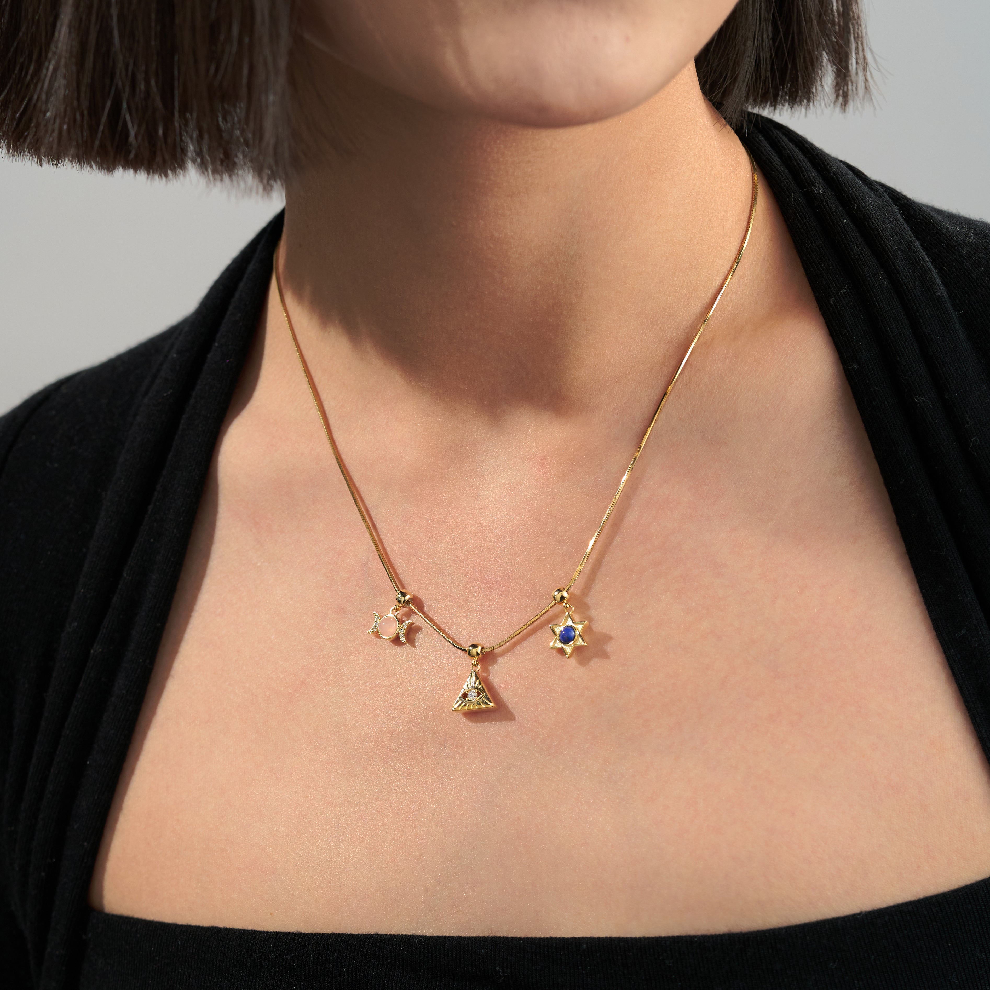 Gold-plated necklace with geometric and star charms worn on woman's neck