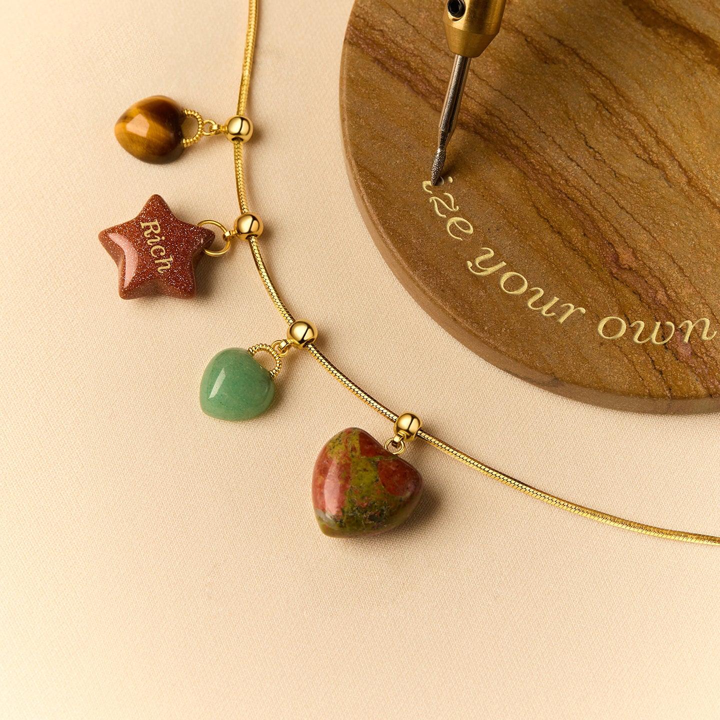 Gold-plated necklace with gemstone heart and star charms on a beige background