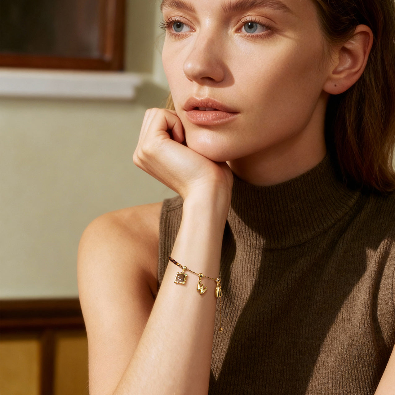 Woman wearing a sleeveless turtleneck top with a gold-plated charm bracelet