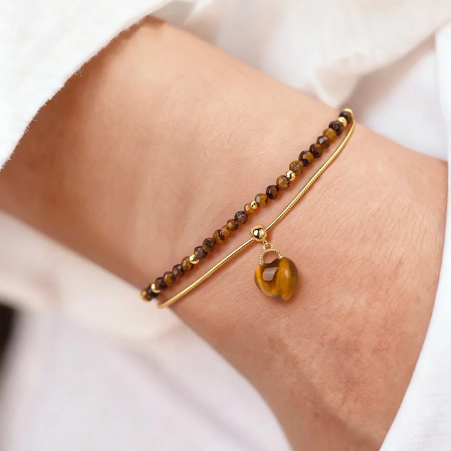 Gold-plated bracelet with brown crystal beads and heart charm on a woman's wrist