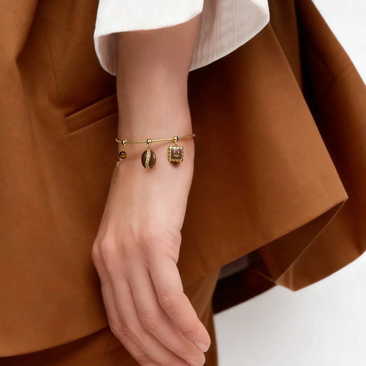 Elegant gold-plated charm bracelet with shell and geometric pendants on a woman's wrist
