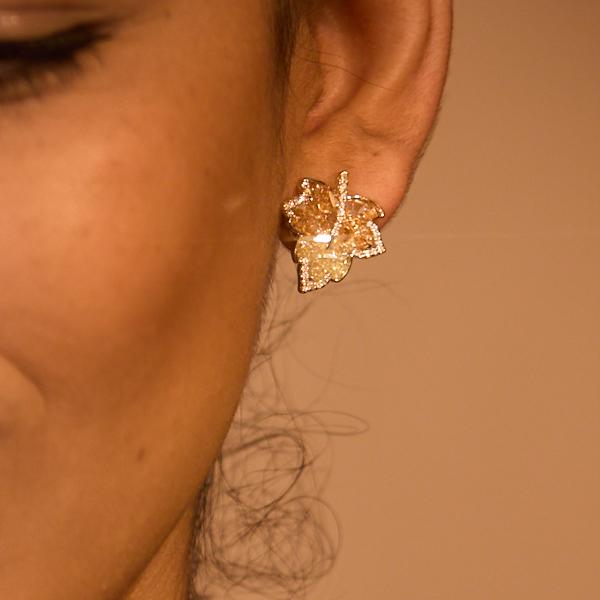 Close-up of a woman's ear wearing a gold-plated leaf-shaped statement earring