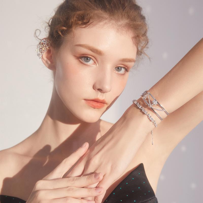 Woman wearing silver layered bracelets and crystal ear cuff, elegant jewelry fashion