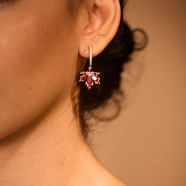 Woman wearing gold-plated statement earring with red gemstones