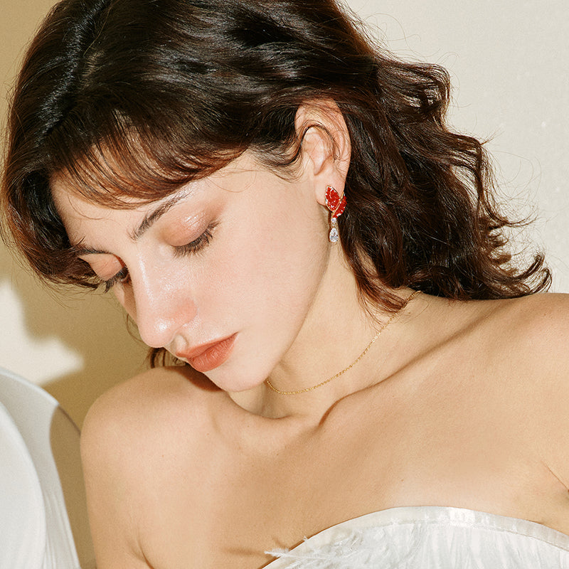 Woman wearing gold-plated necklace and red statement earrings, elegant jewelry styling