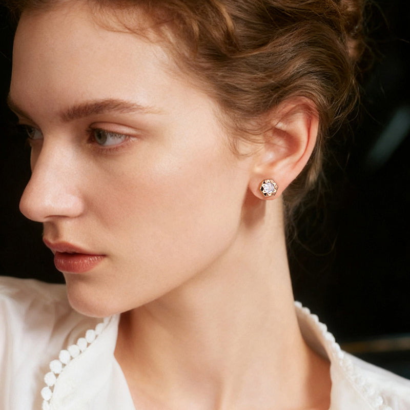 Woman wearing elegant gold-plated stud earrings with clear round gemstone