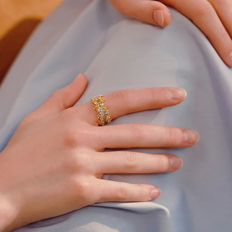 Gold-plated statement ring with sparkling crystals on woman's finger, elegant jewelry style