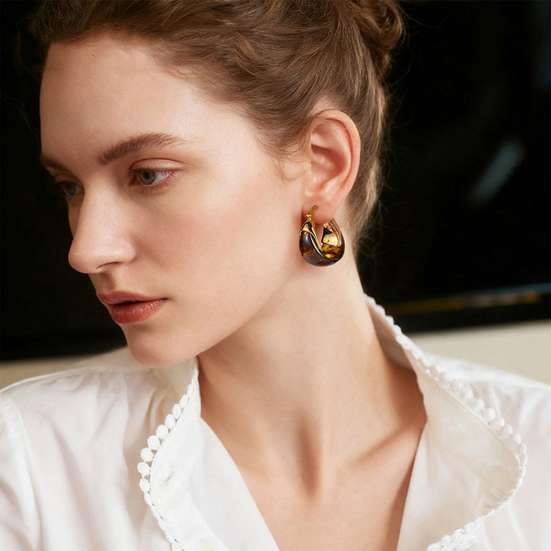 Woman wearing gold-plated statement hoop earrings with tortoise pattern, elegant style