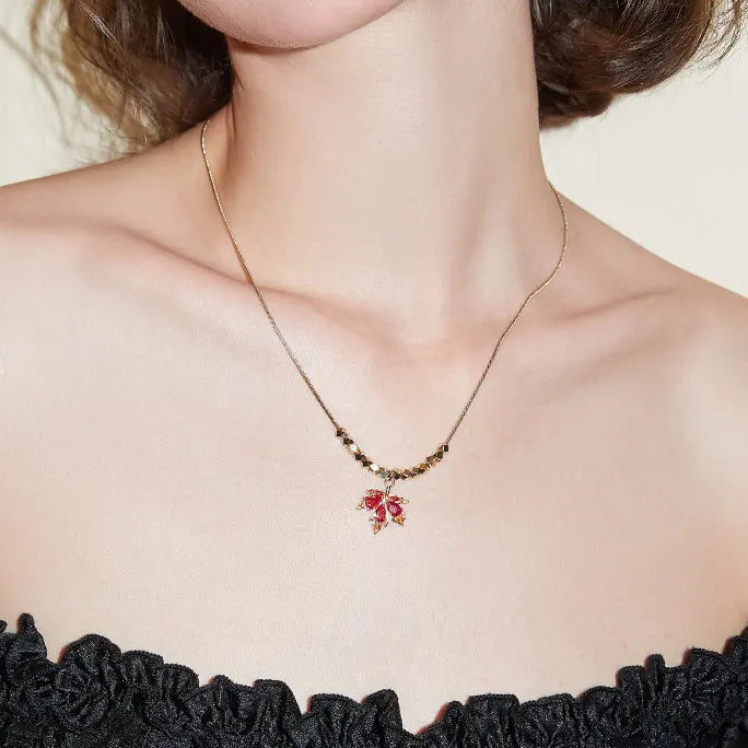 Gold-plated necklace with red gemstone floral pendant on a woman in a black off-shoulder top