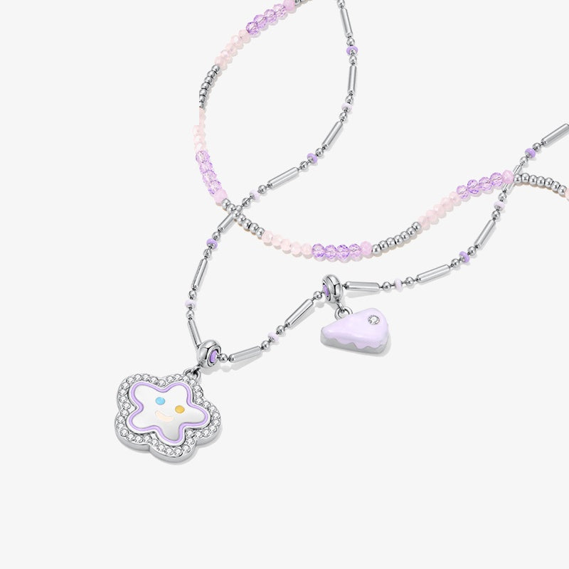 Pastel beaded necklace with silver accents, star and cake slice charms on white background