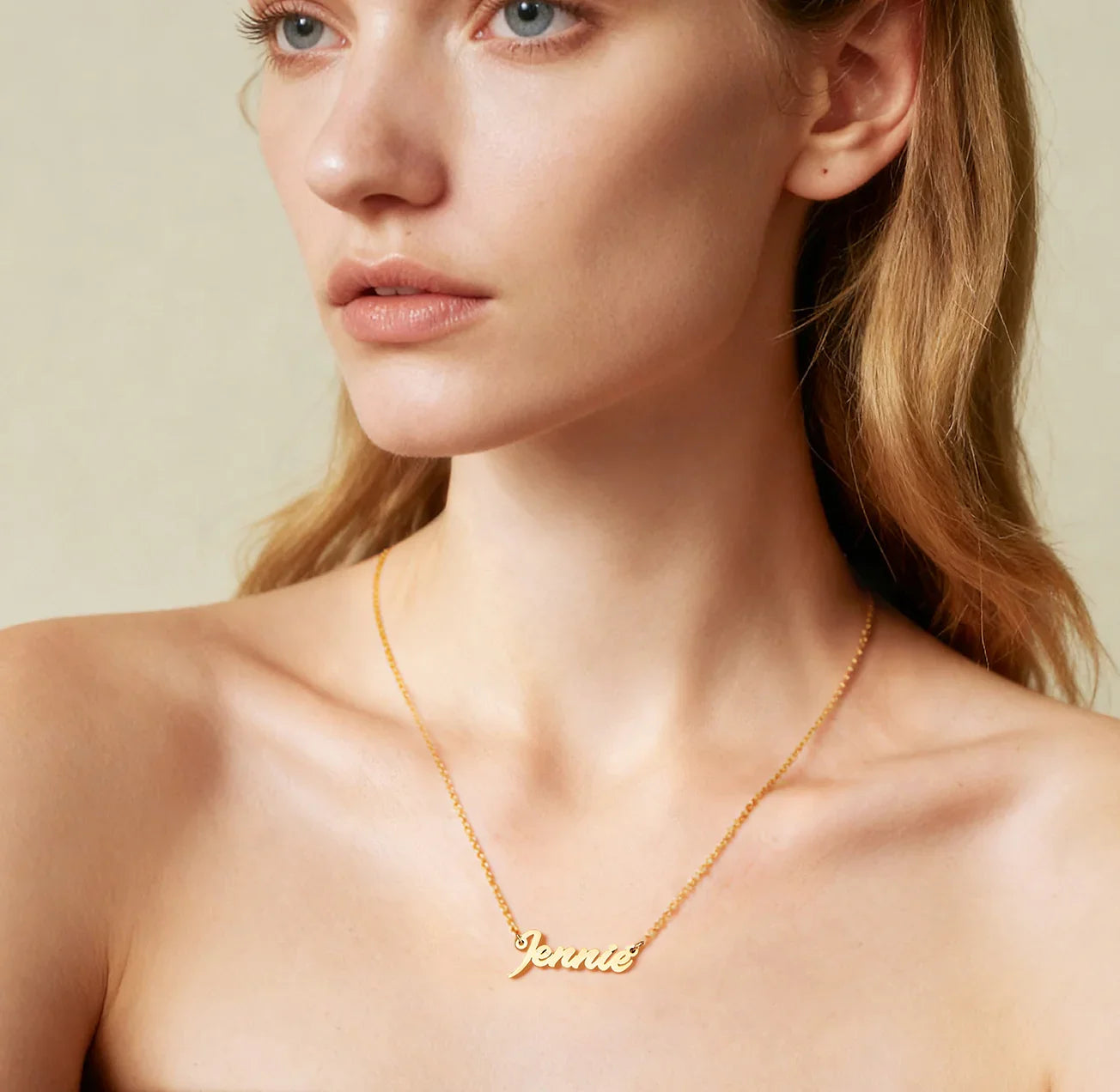 Woman wearing gold-plated name necklace with 'Jennie' script on delicate chain