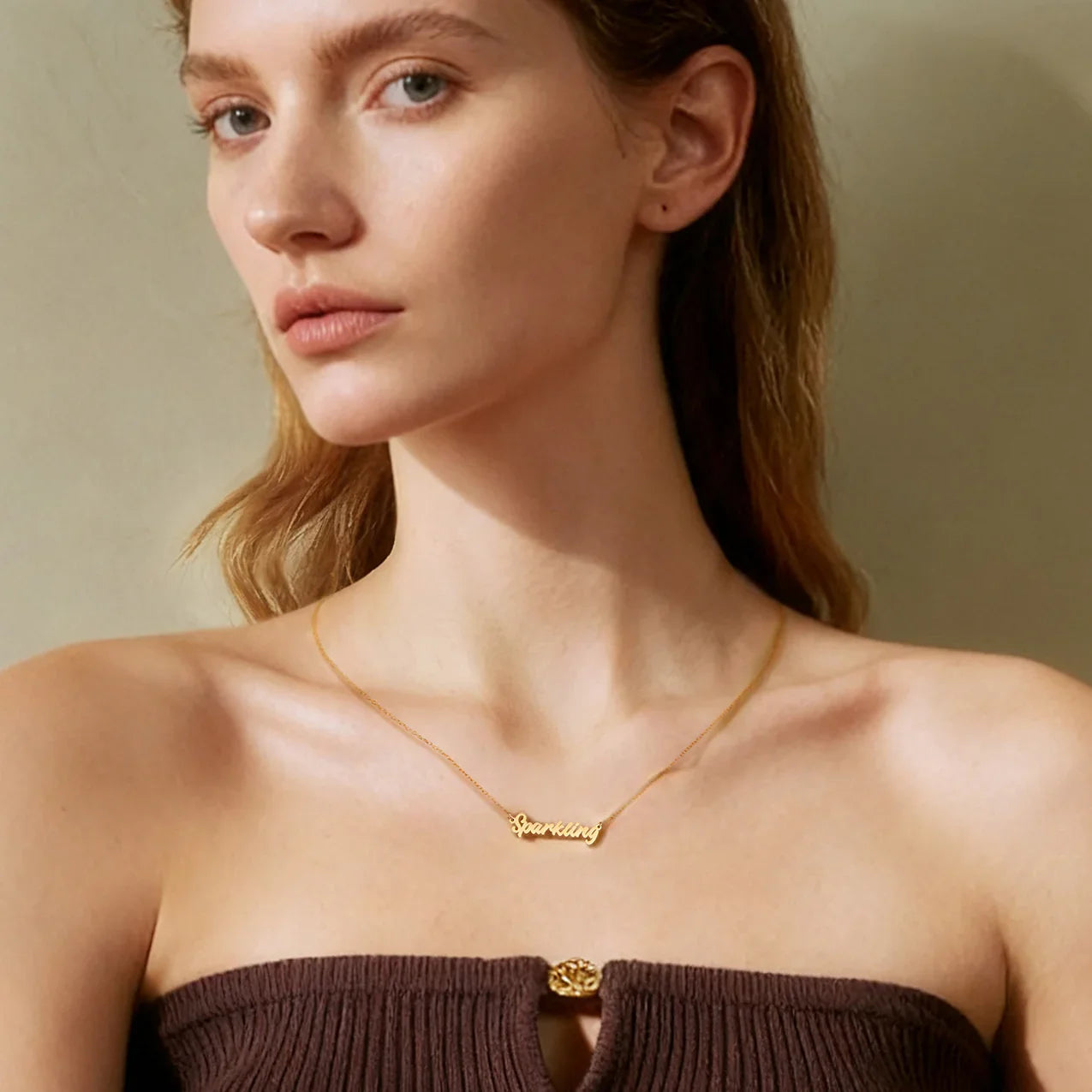 Woman wearing a gold-plated 'Sparkling' pendant necklace and brown strapless top