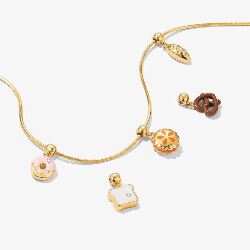 Gold-plated necklace with bakery-themed charms, including donut, toast, pretzel, and pie designs.