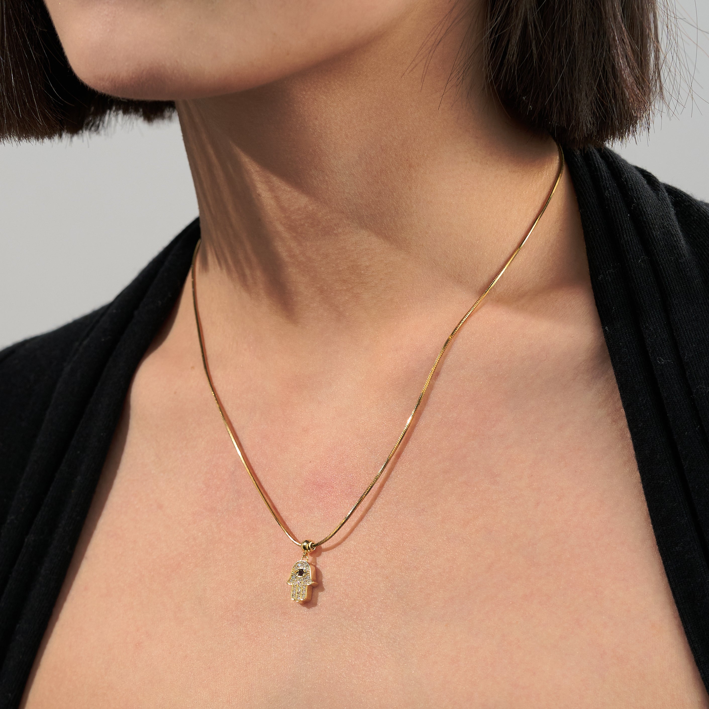Gold-plated Hamsa pendant necklace on woman's neck, minimalist jewelry style