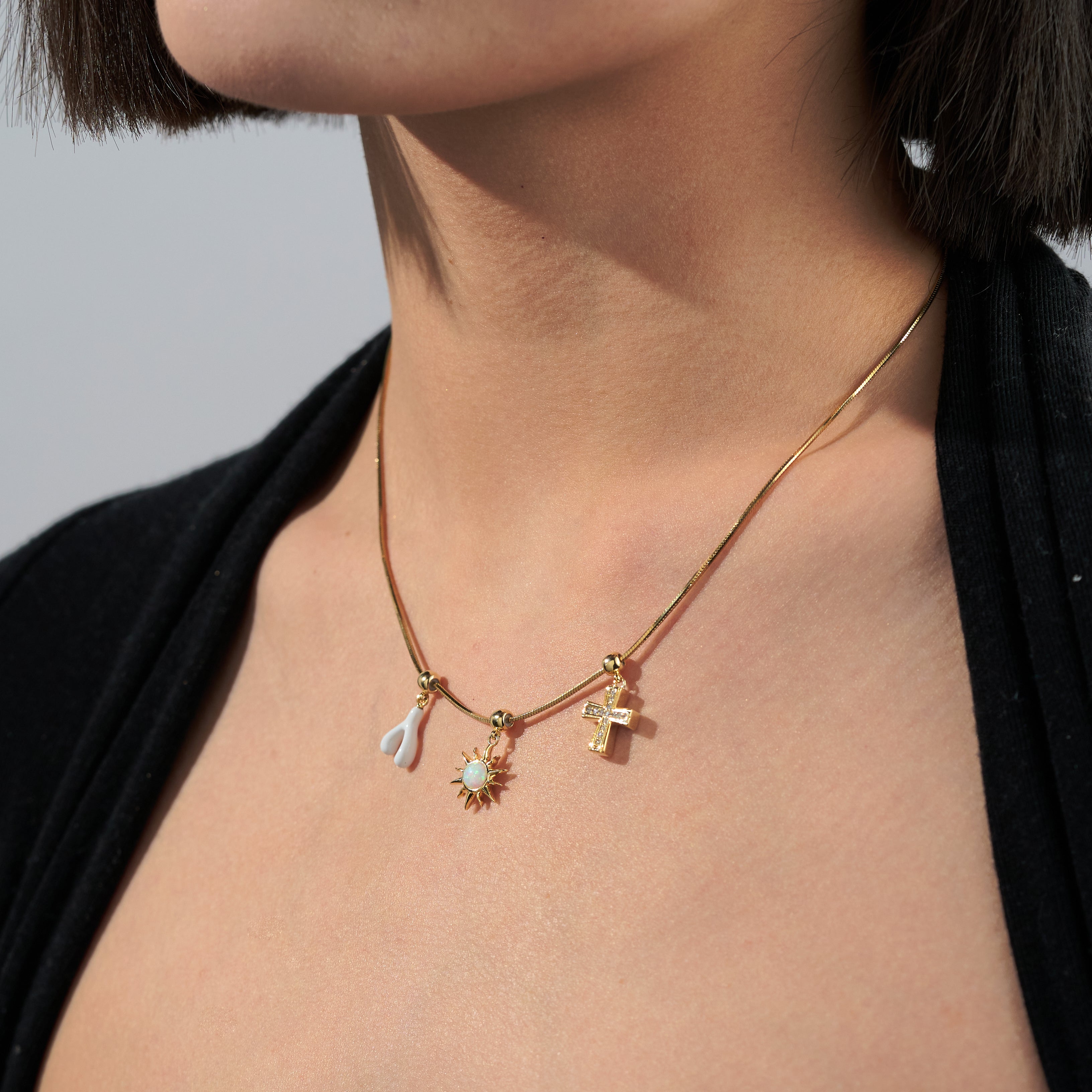 Gold-plated necklace with three unique pendants on a woman's neck, close-up style
