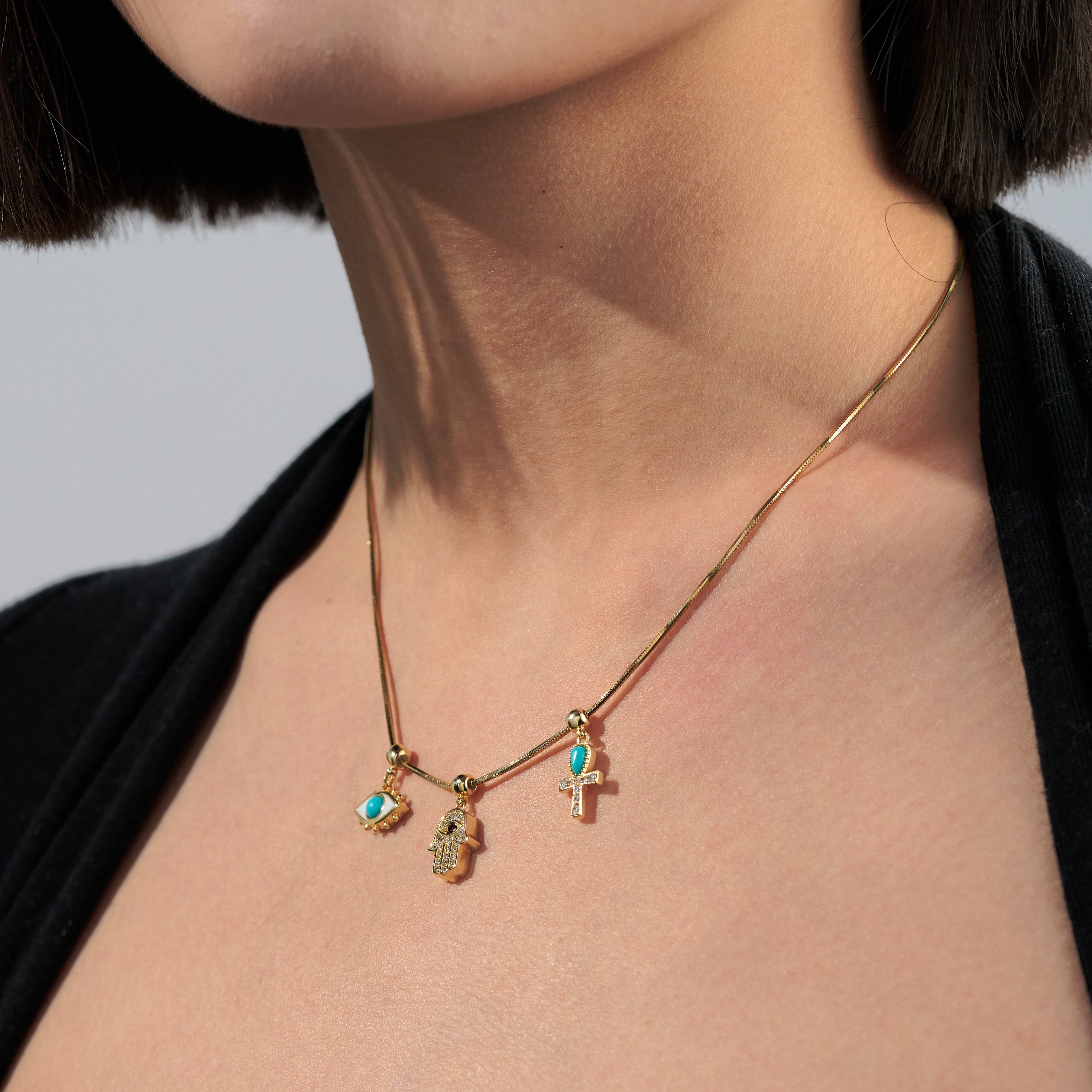 Gold-plated necklace with turquoise charms and symbols on a woman's neck
