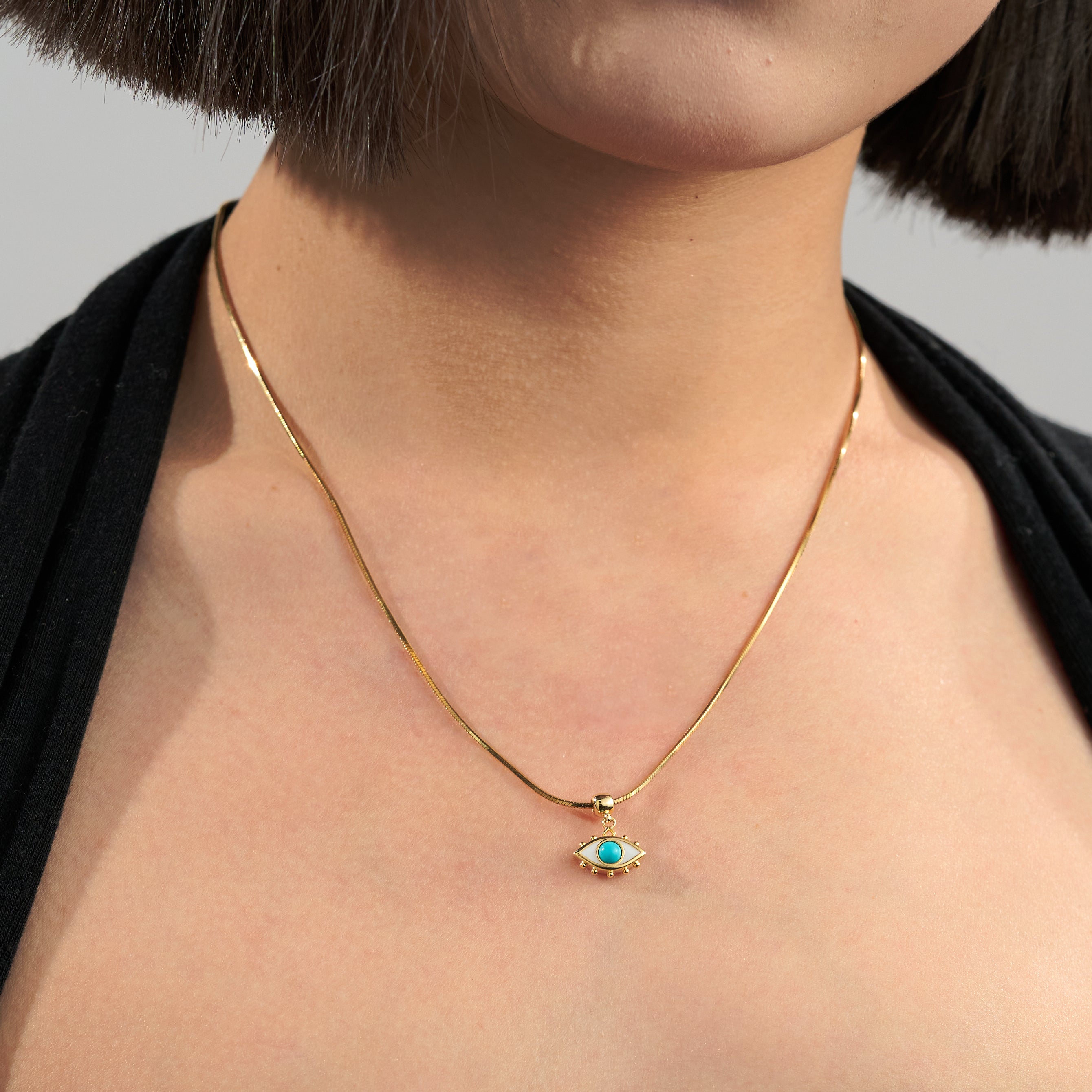 Gold-plated necklace with turquoise evil eye pendant on woman's neck
