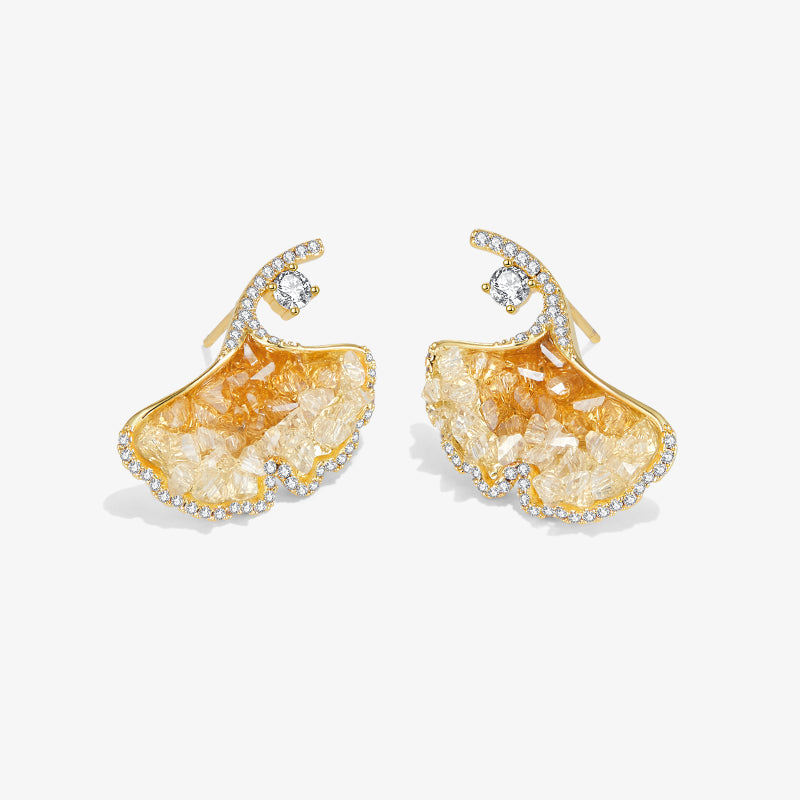 Gold-plated statement earrings with crystal accents and textured leaf design on white background