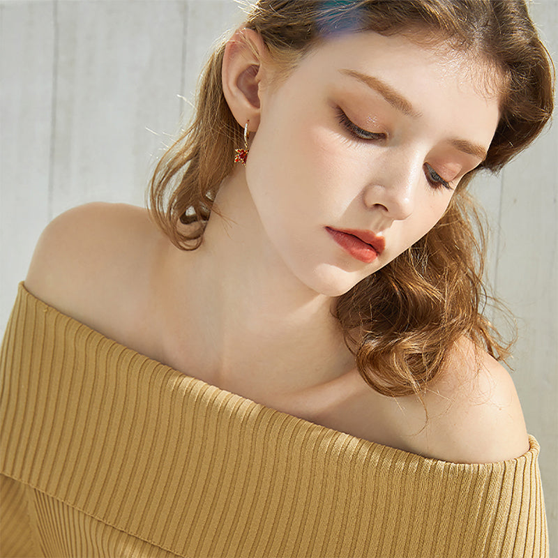 Woman wearing off-shoulder ribbed top and gold hoop statement earrings