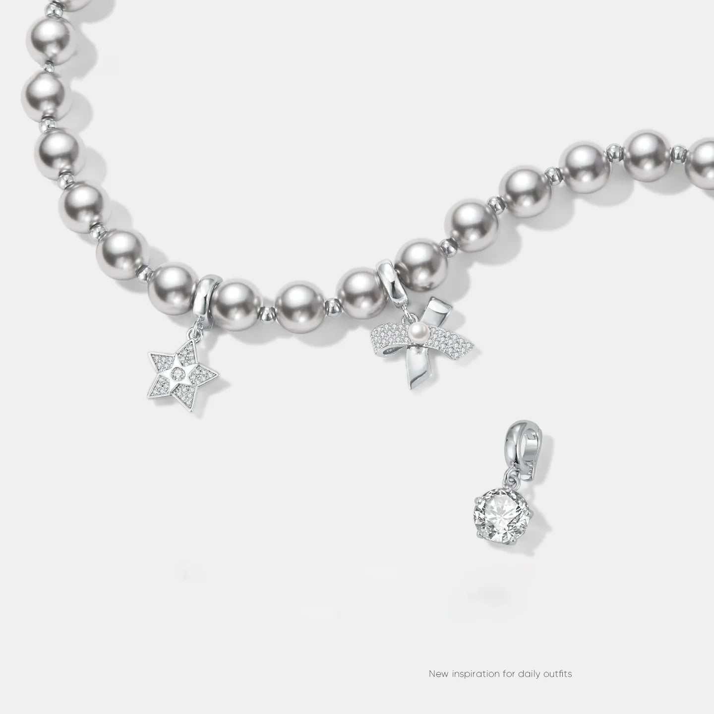 Silver pearl beaded necklace with star, bow, and crystal charms on white background