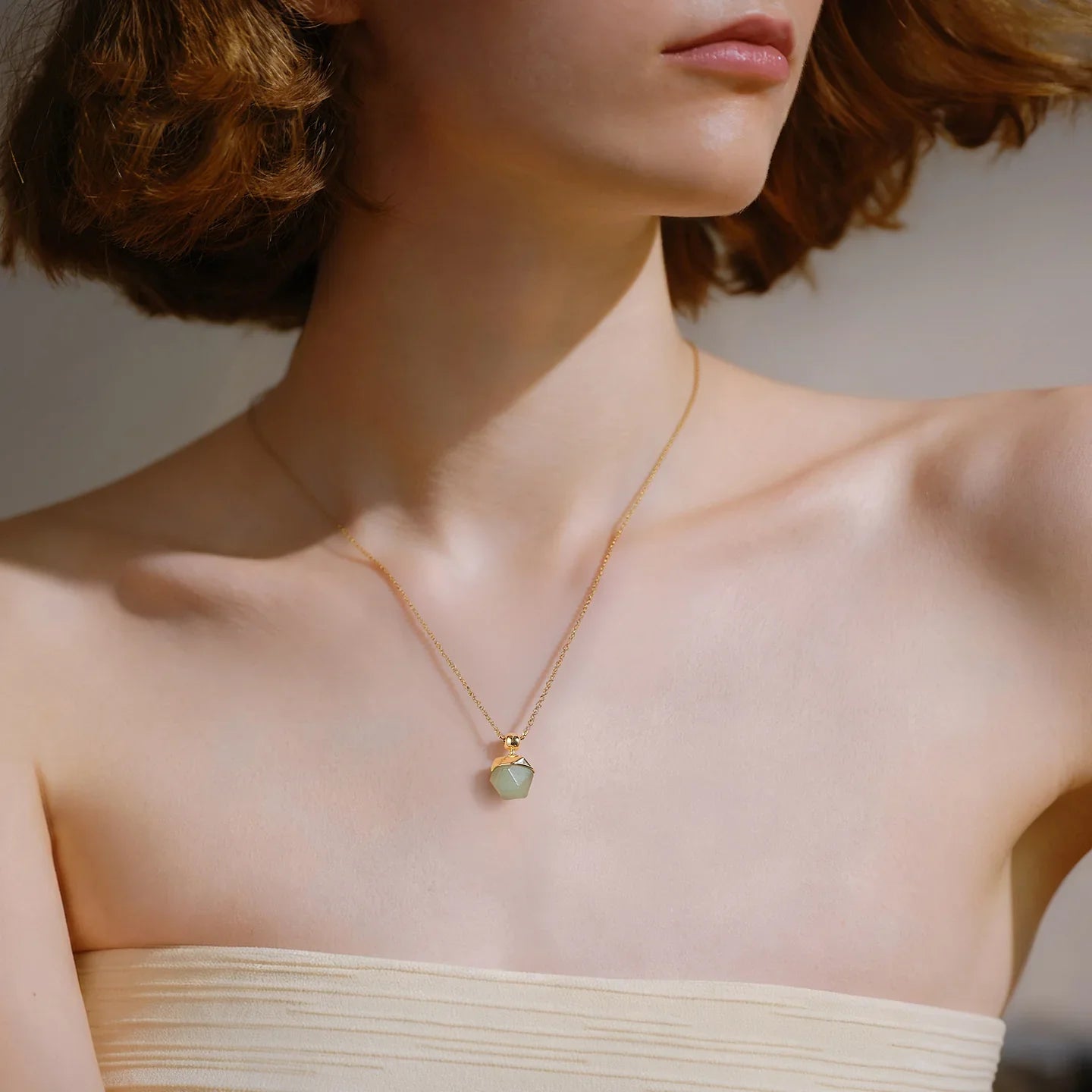 Woman wearing gold-plated necklace with green geometric pendant, elegant jewelry close-up