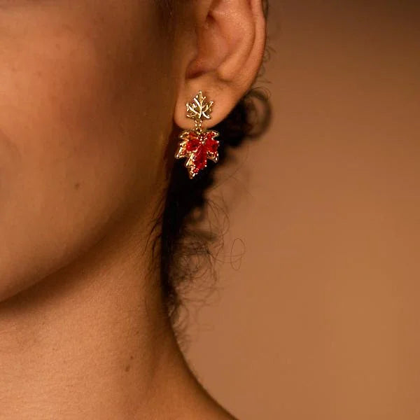 Gold-plated leaf earrings with red gemstone on woman's ear, close-up view