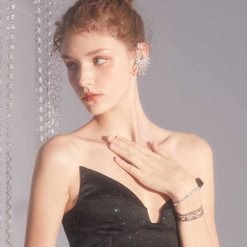 Woman in a black strapless dress wearing a statement crystal ear cuff and layered bracelets