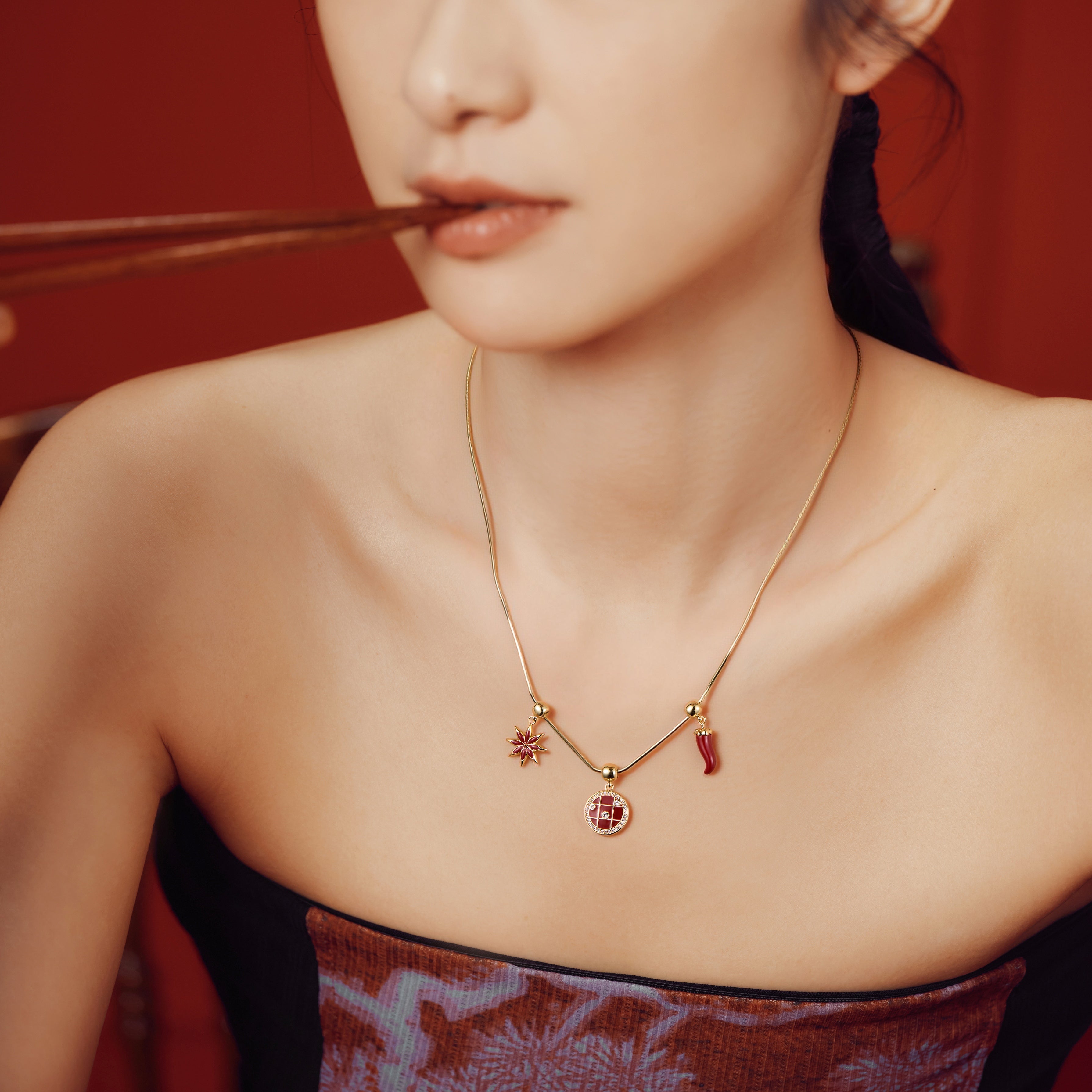 Woman wearing gold-plated pendant necklace with red charms and strapless dress