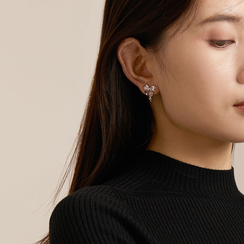 Elegant woman wearing crystal floral statement earrings against neutral background