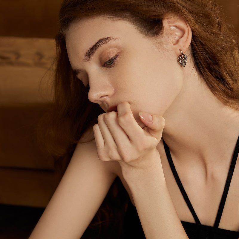 Woman wearing gold-plated heart-shaped statement earring, elegant style