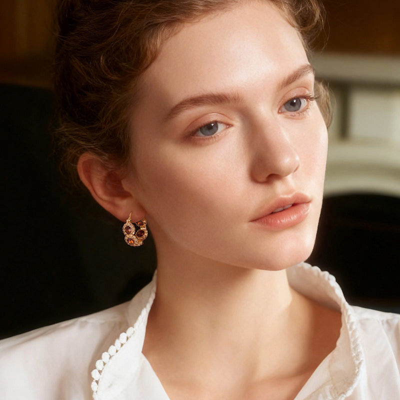 Woman wearing gold-plated hoop earrings with gemstone accents, elegant jewelry style