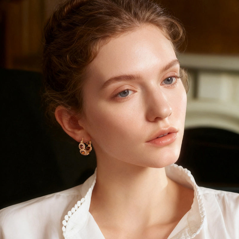 Woman wearing gold-plated hoop earrings with gemstone accents, elegant jewelry style