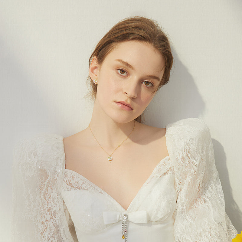 Woman in white lace dress wearing gold-plated necklace and elegant statement earrings