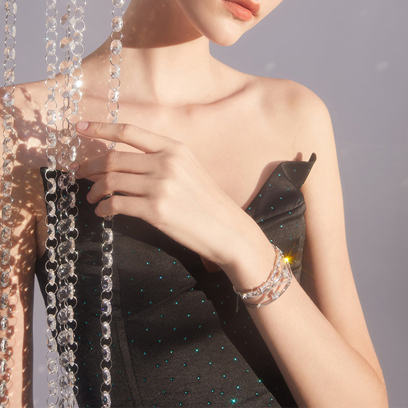 Elegant woman in black dress wearing sparkling layered bracelet with crystal chains