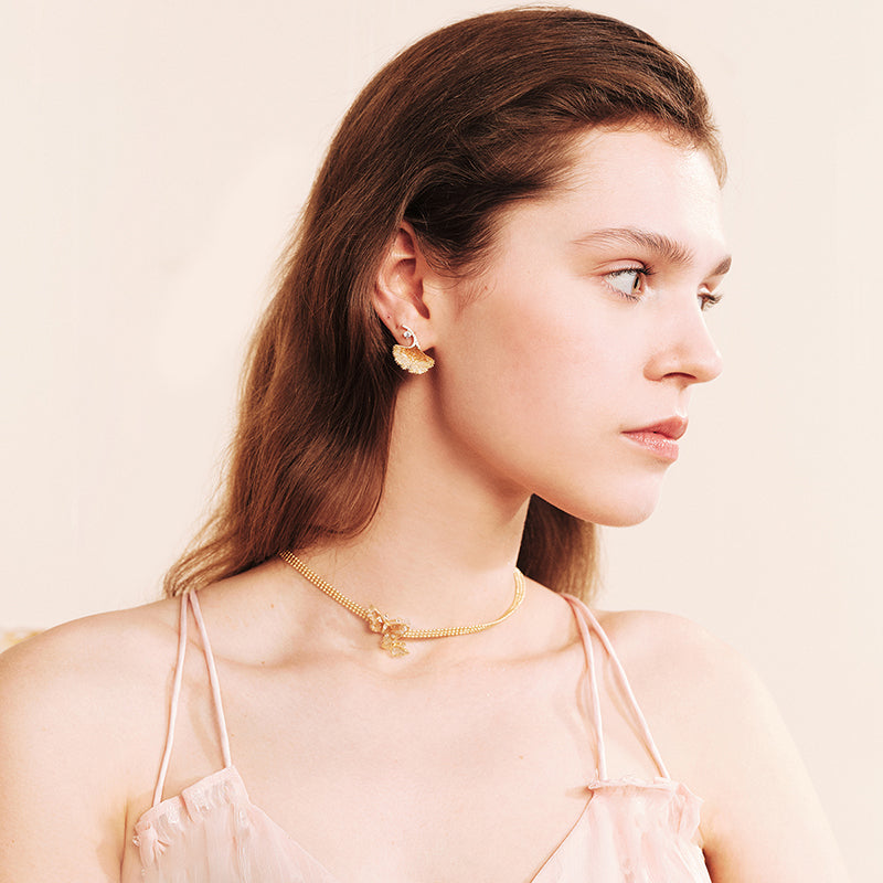 Woman wearing gold-plated statement earrings and a gold choker necklace with pendant
