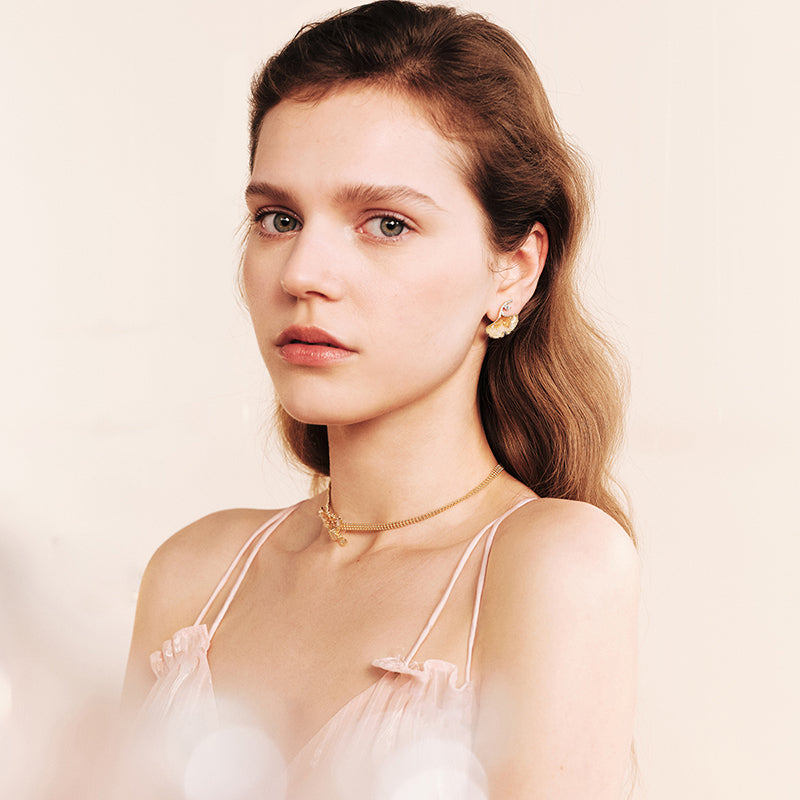 Woman wearing a gold-plated choker necklace and statement gold earrings