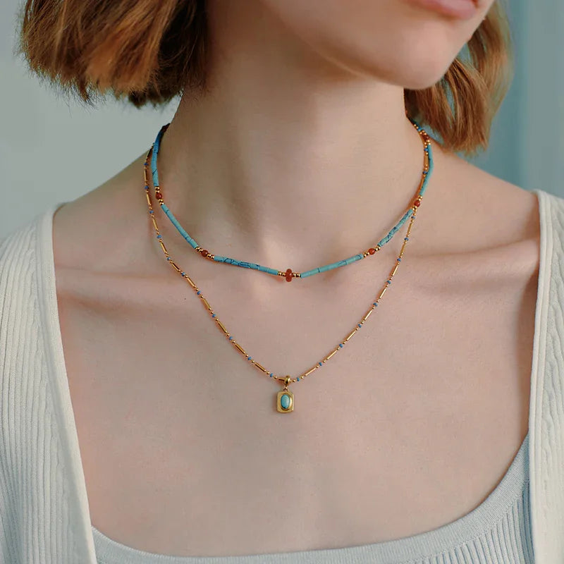 Layered gold-plated necklaces with turquoise beads and turquoise pendant on woman's neck