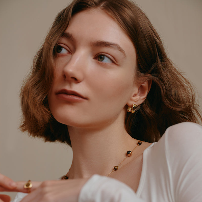 Woman wearing gold-plated statement earrings and elegant beaded necklace