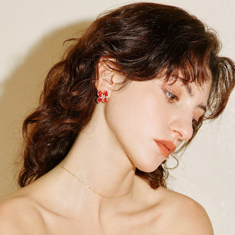 Woman wearing gold necklace and statement red flower stud earrings