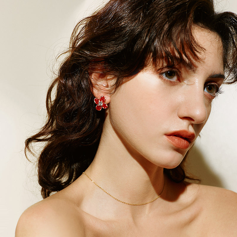 Woman wearing red flower stud earrings and a delicate gold-plated necklace